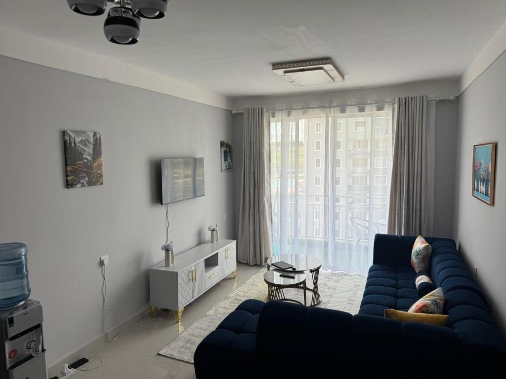 a living room with a blue couch and a large window at EM Homes Modern 1-Bedroom Apartment with Pool 15 Minutes from JKIA Airport in Marimbeti