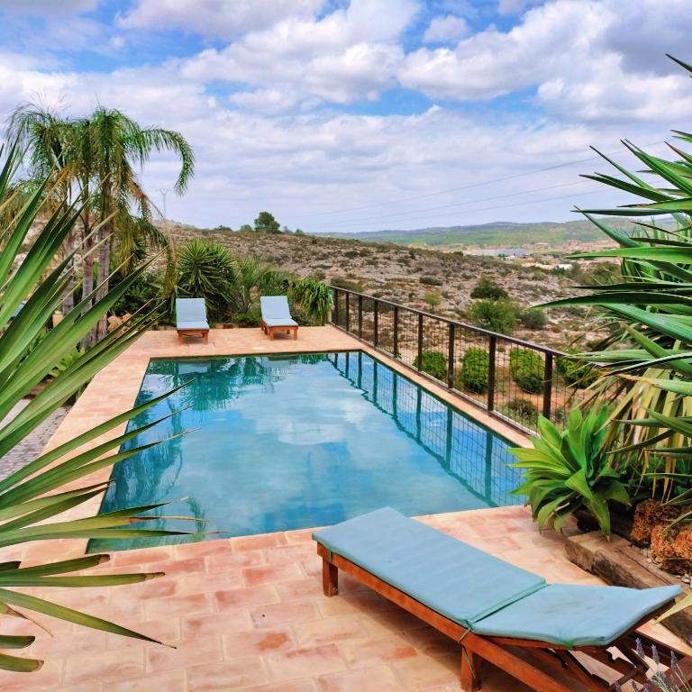 a swimming pool with two lounge chairs next to a fence at Villamasai "Un pedacito de África en Valencia" in Valencia