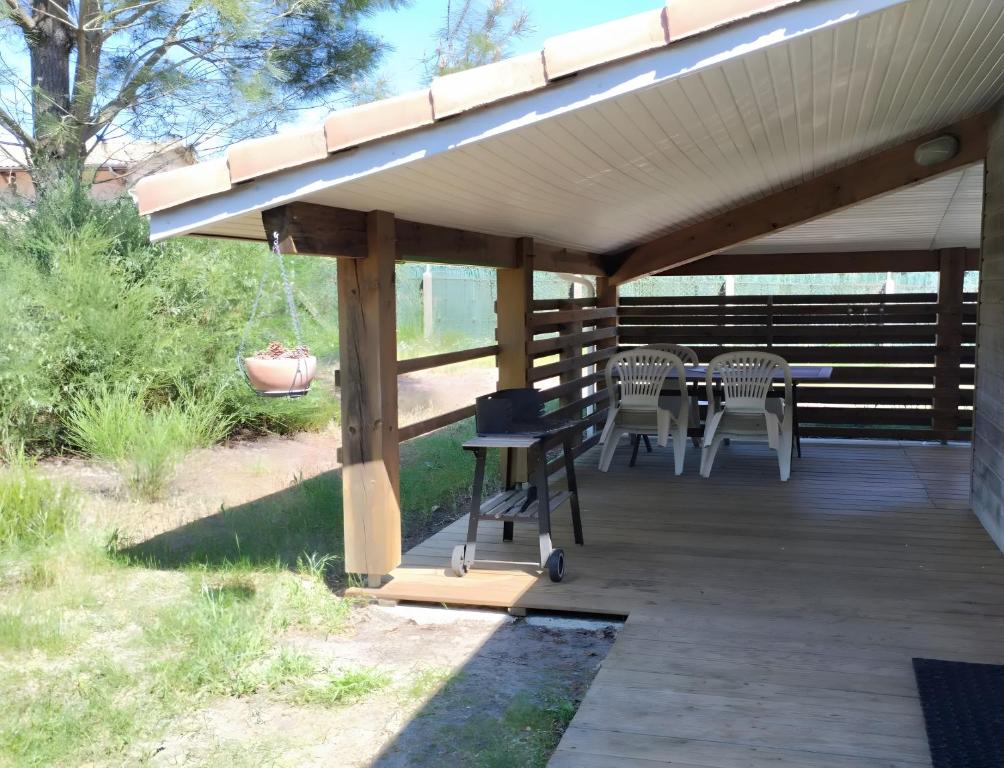 a pergola with chairs and a table on a deck at Appartement 4p Sanguinet-Doum Doum in Sanguinet