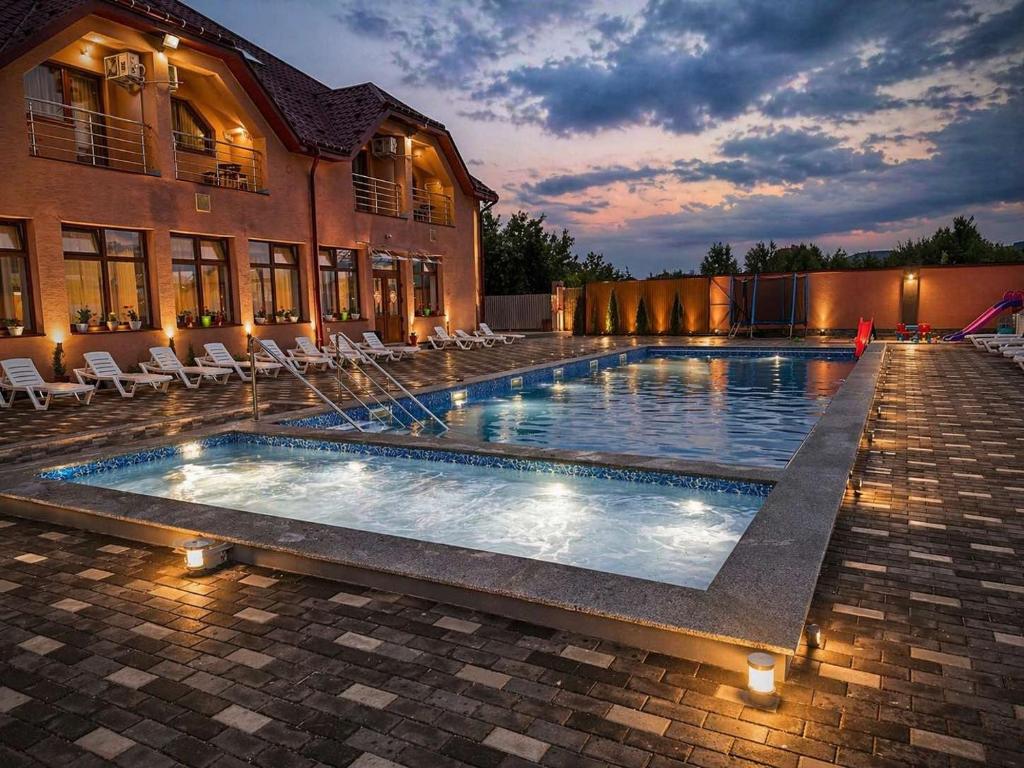 a large swimming pool with chairs and a building at HotelVizit in Solotvyno