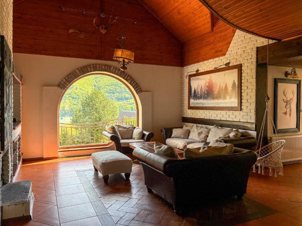 a living room with couches and a large window at Willa Wypoczynkowa in Międzybrodzie Bialskie