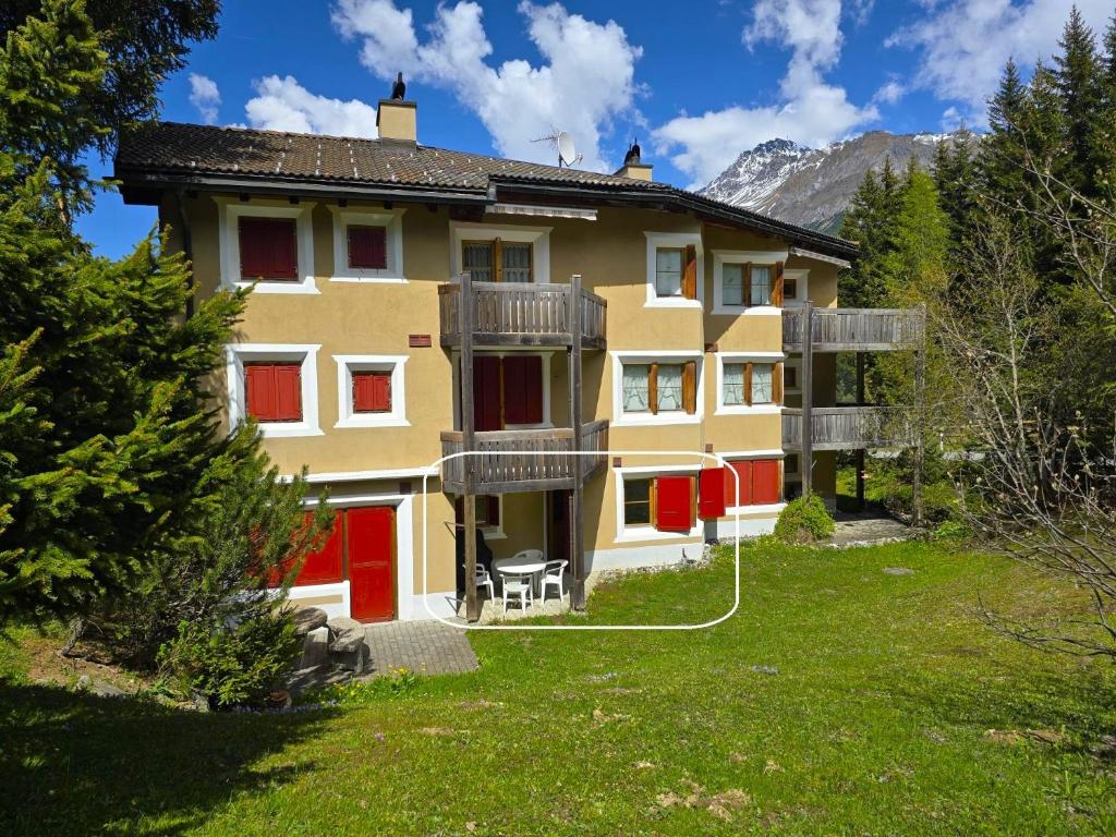 a large building with red doors and a yard at Ferienwohnung Selva in Lenzerheide