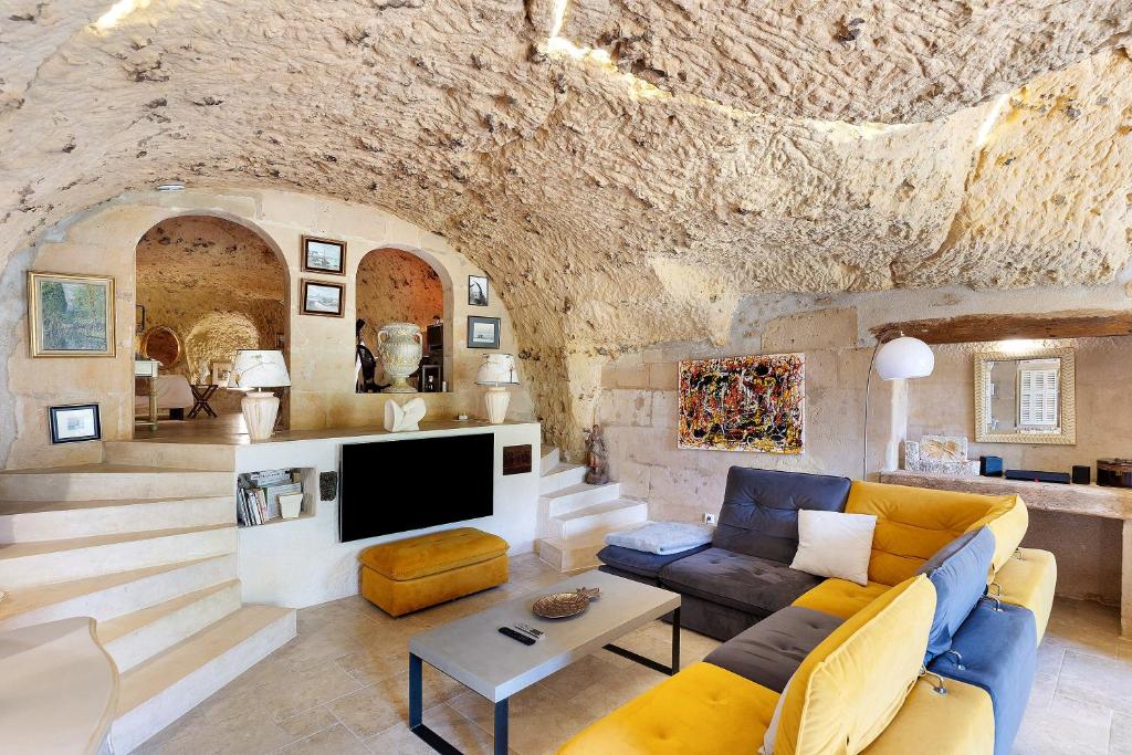 a living room with a couch and a tv at Les Iris - Maison Troglodytique in Trôo