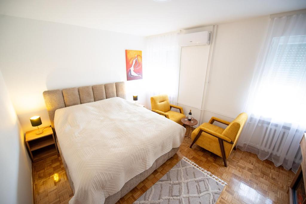 a bedroom with a white bed and two chairs at Apartman Gorica in Priboj