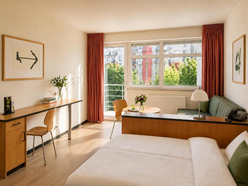 a living room with a bed and a desk in a room at Hotel Am Weberplatz in Dresden