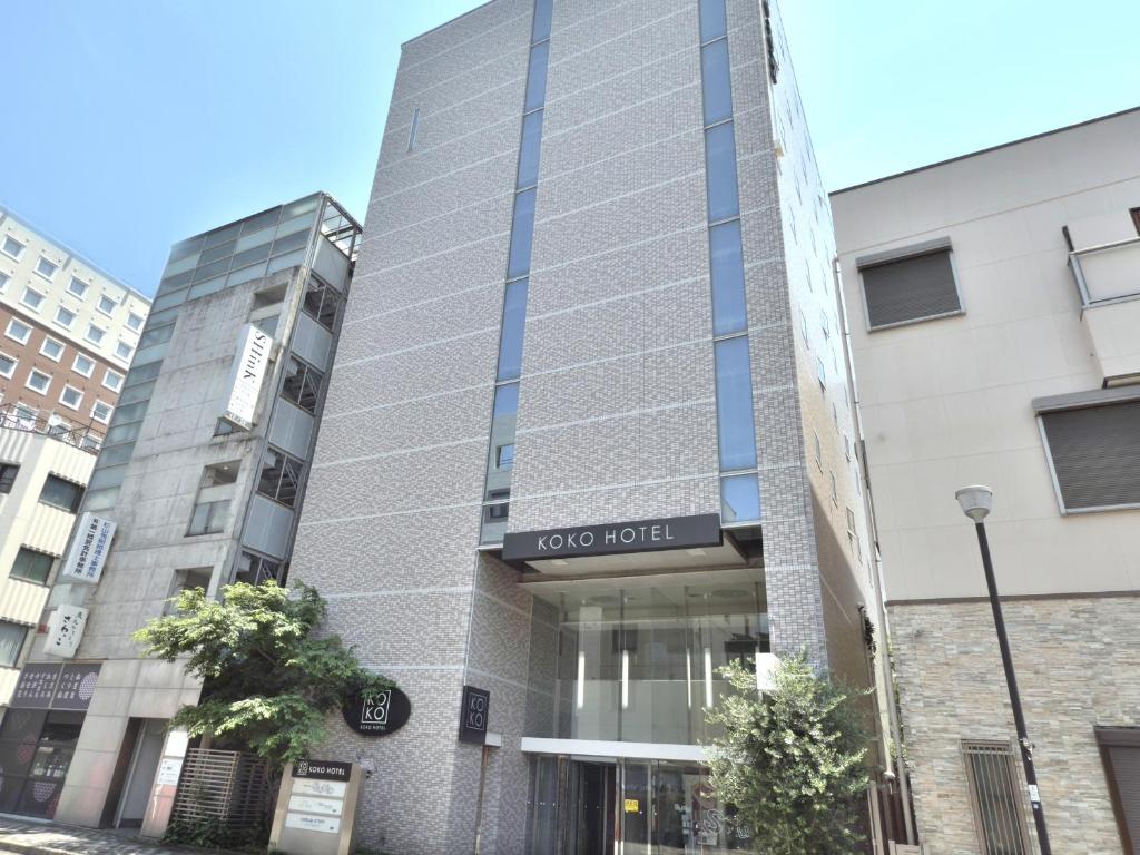 a building with a sign for a hotel at KOKO HOTEL Numazu Ekimae in Numazu