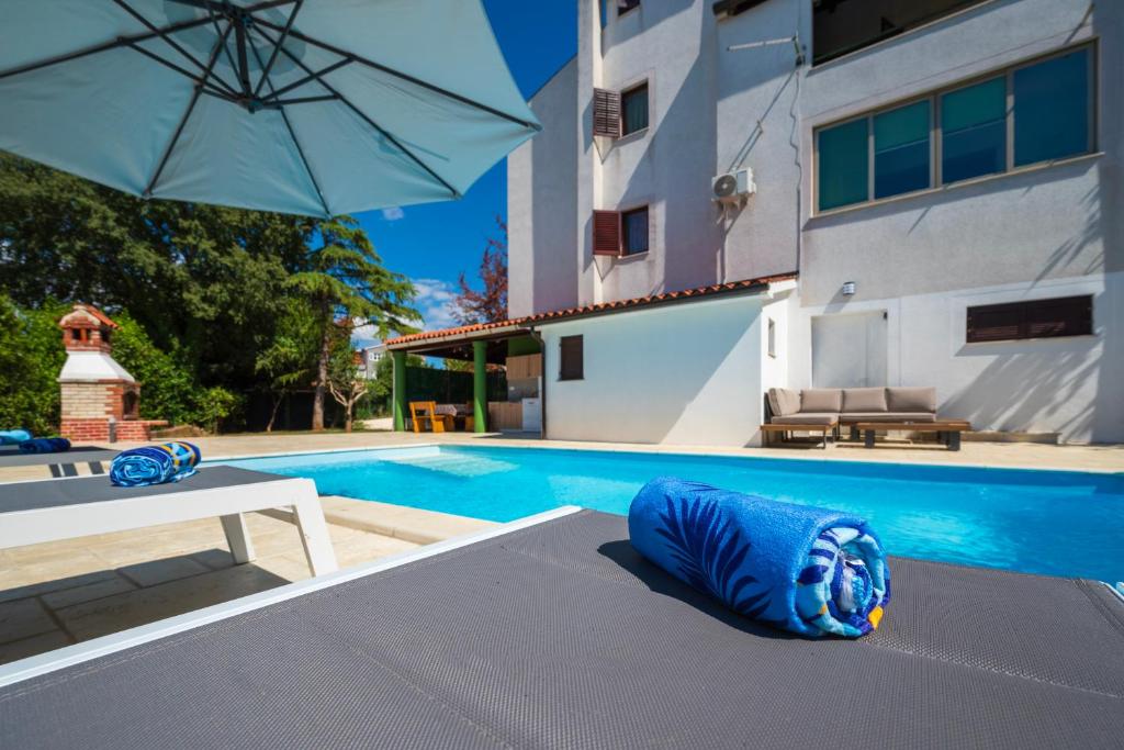 a swimming pool with a blue pillow and an umbrella at Moonvidal residence with big private swimming pool and free parking in Pula