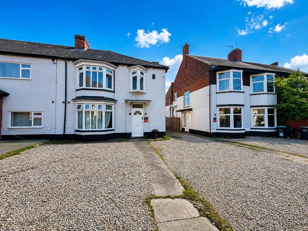 two white houses with a driveway in front of them at Middlesbrough The Longlands Hotel in Middlesbrough