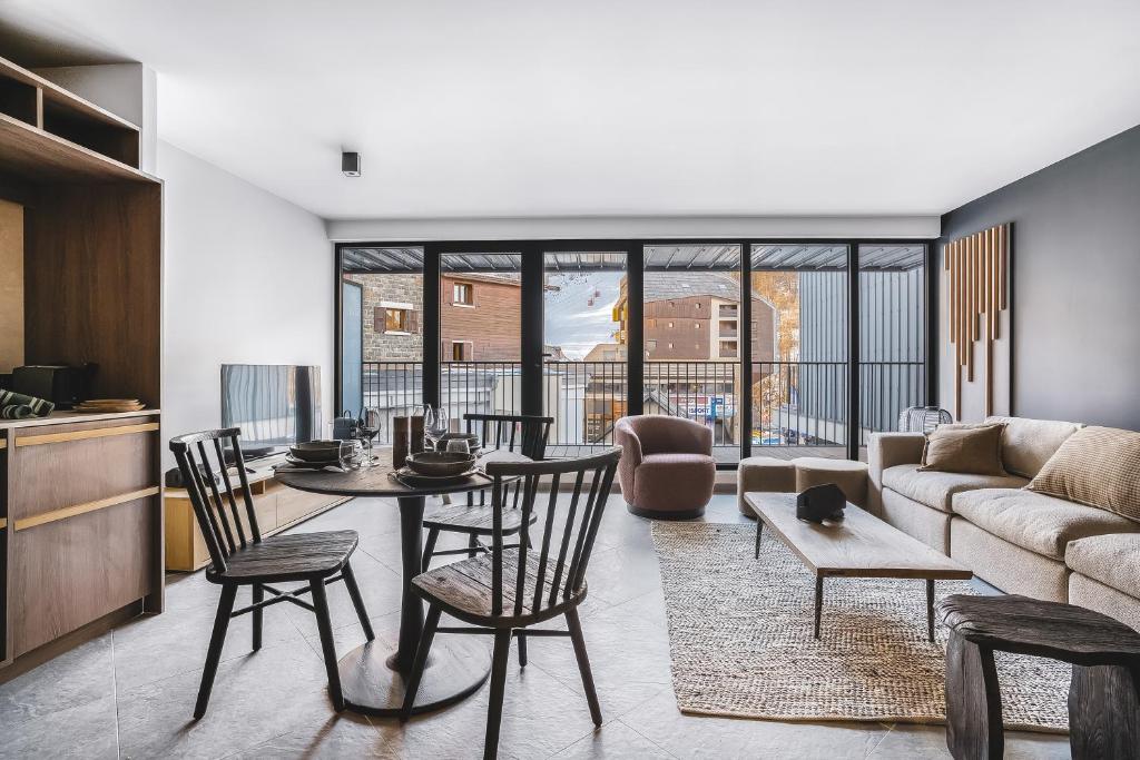 a living room with a couch and a table and chairs at Les Chalets du Grand Hôtel in Saint-Chaffrey