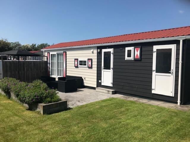 a small black and white house with a yard at Chaletverhuur-Olmenduin in Serooskerke