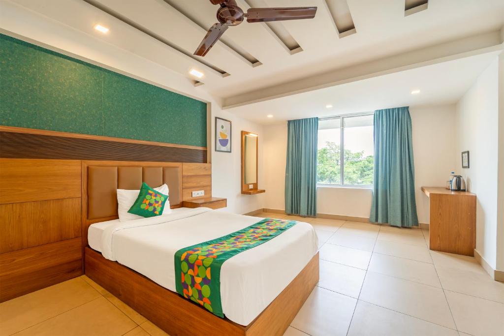 a bedroom with a bed and a greenboard on the wall at Treebo Medco Mansion in Kozhikode