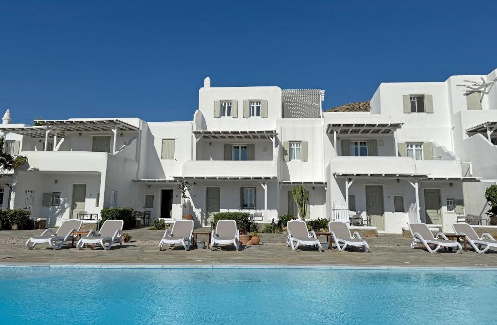 a large white building with chairs and a swimming pool at Yakinthos Suites in Mykonos
