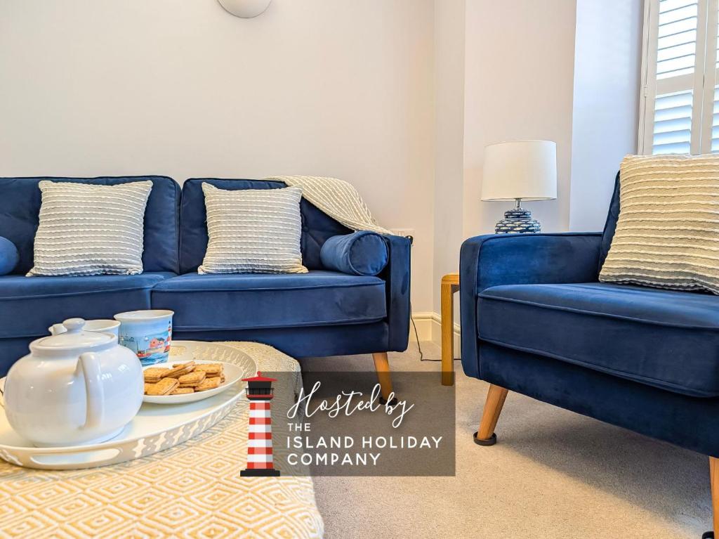 a living room with two blue couches and a tray of cookies at Sandlands - Perfect central location in Ryde