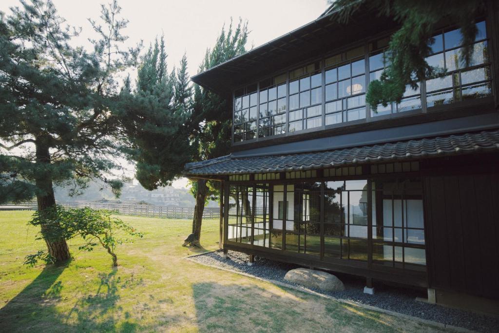 a building with glass windows and a tree at 旧雨今雨 in Onomichi