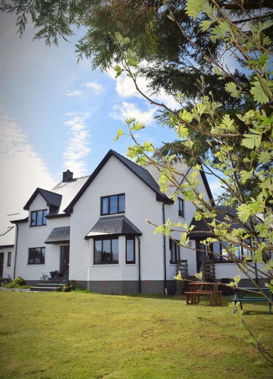 a large white house with a picnic table in front of it at Benview House in Staffin
