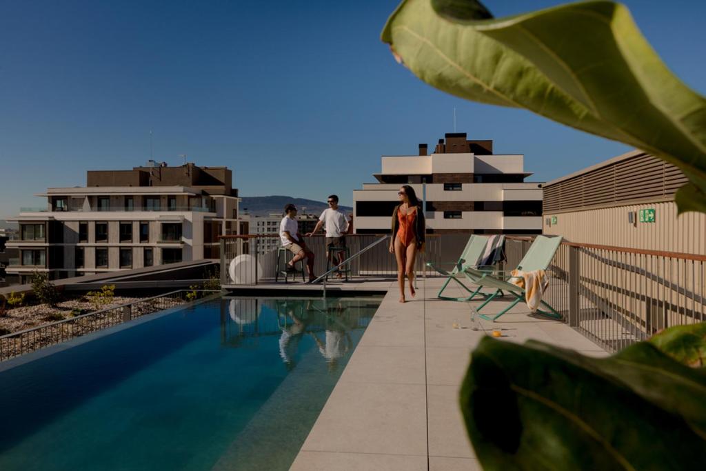 a woman walking on the roof of a building next to a swimming pool at Kora Kiliki in Pamplona