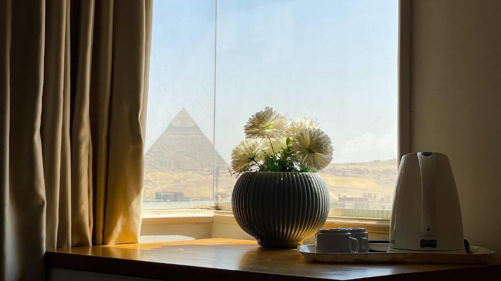 a vase on a window sill with a view of the pyramid at luxurios hotel with pyramids view in Cairo
