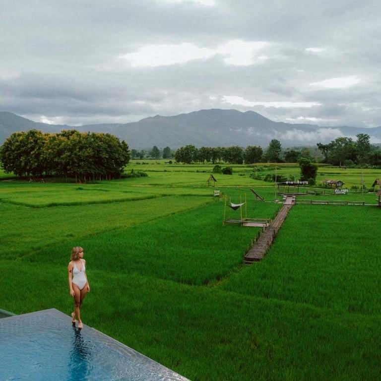a woman standing on the edge of a swimming pool at Sangthong Resort at Chiang Klang in Chiang Klang