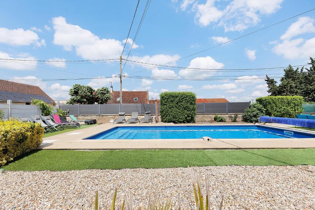 a swimming pool in a yard with chairs around it at Le Gîte des Anges - 12pers, Piscine in Angé