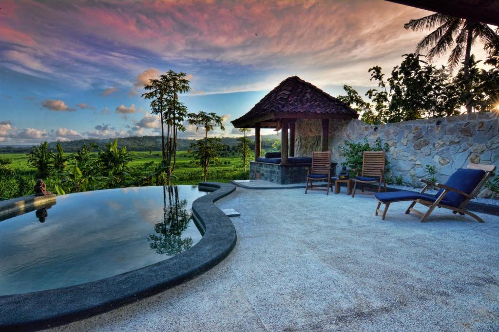 a swimming pool with chairs and a gazebo at Villa Blue Steps in Yogyakarta
