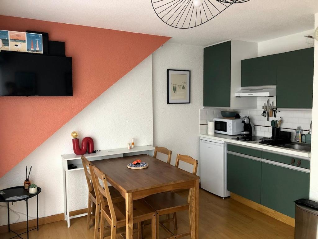 a kitchen with a table and a kitchen with green cabinets at Studio centre ville - 5min de la plage in Neufchâtel-Hardelot