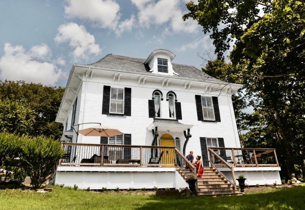 people standing on the porch of a white house at The Montague Rose Inn & Cafe in Saint Andrews