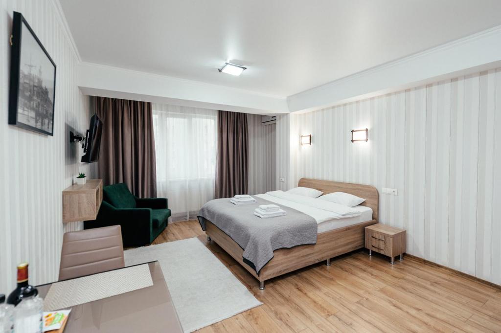 a bedroom with a bed and a green chair at Apart Hotel Anastasia in Chişinău