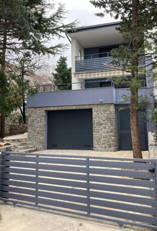 a house with two garage doors and a fence at 20 Koraka in Klenovica