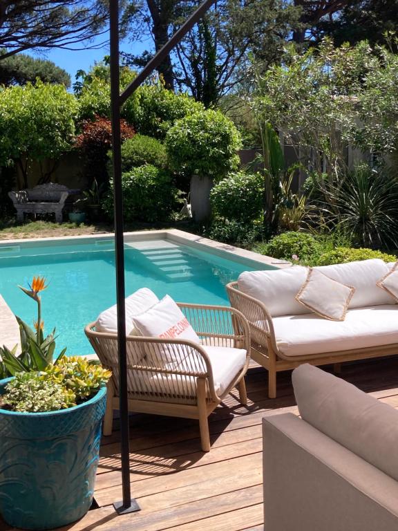 a pool with two chairs and a couch and an umbrella at La Vagabonde in Saint-Tropez