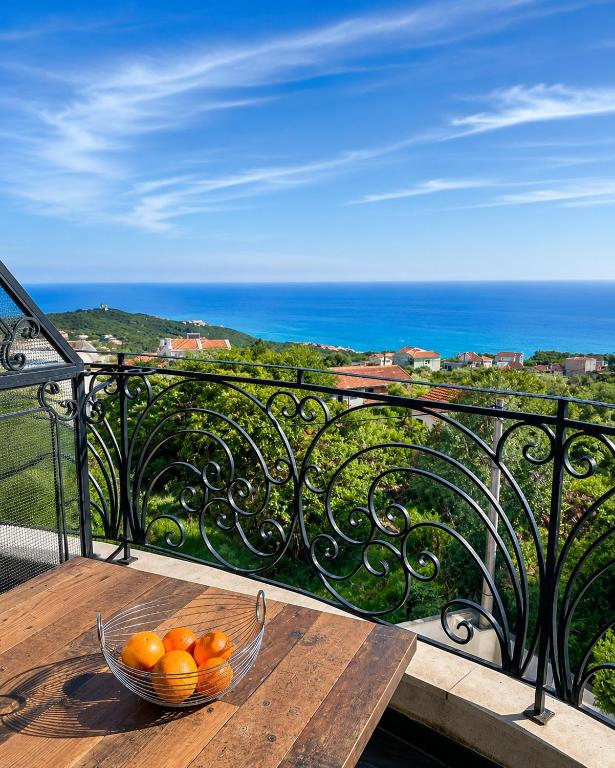 a bowl of oranges sitting on a table on a balcony at Krimovica Sunset Spacious Apartment with Sea View and Pool in Krimovice