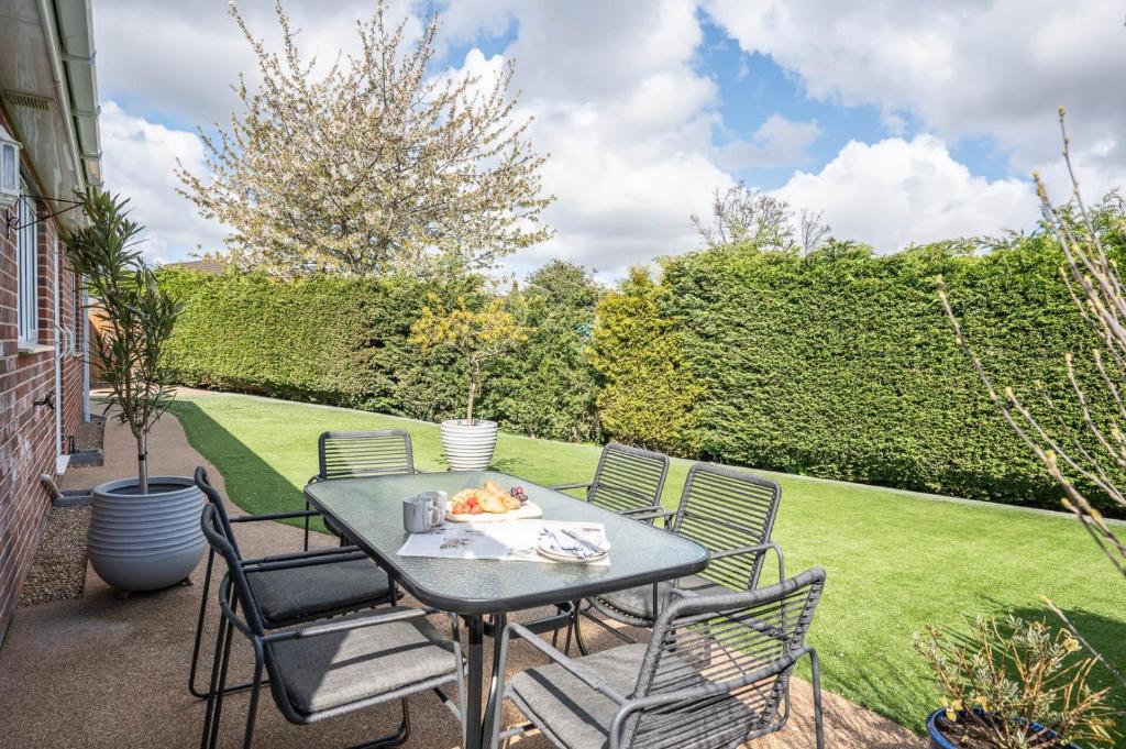 a table and chairs on a patio with a lawn at Boyd’s Bungalow, Lowestoft in Lowestoft