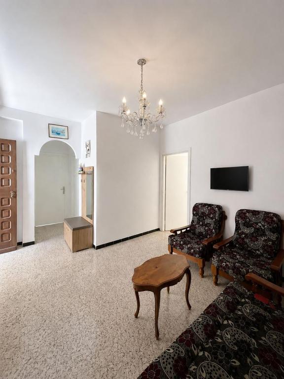 a living room with a couch and a chair and a chandelier at La maison douce Bizerte in Bizerte