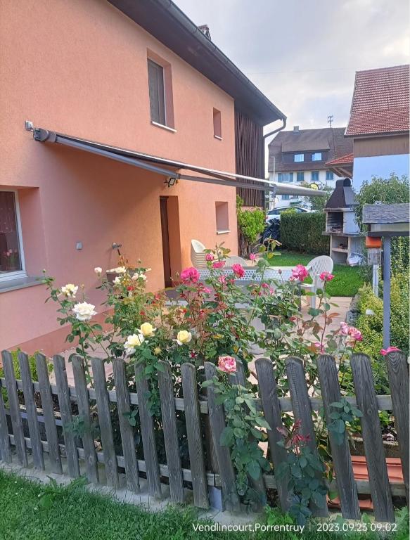 a wooden fence in front of a house with flowers at BnB LES OISEAUX, chez Lidia, 26m2 à 44m2, 2ème étage in Vendlincourt