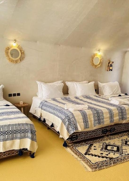 a bedroom with two beds and two mirrors on the wall at Sahara Luxe Camp in Merzouga