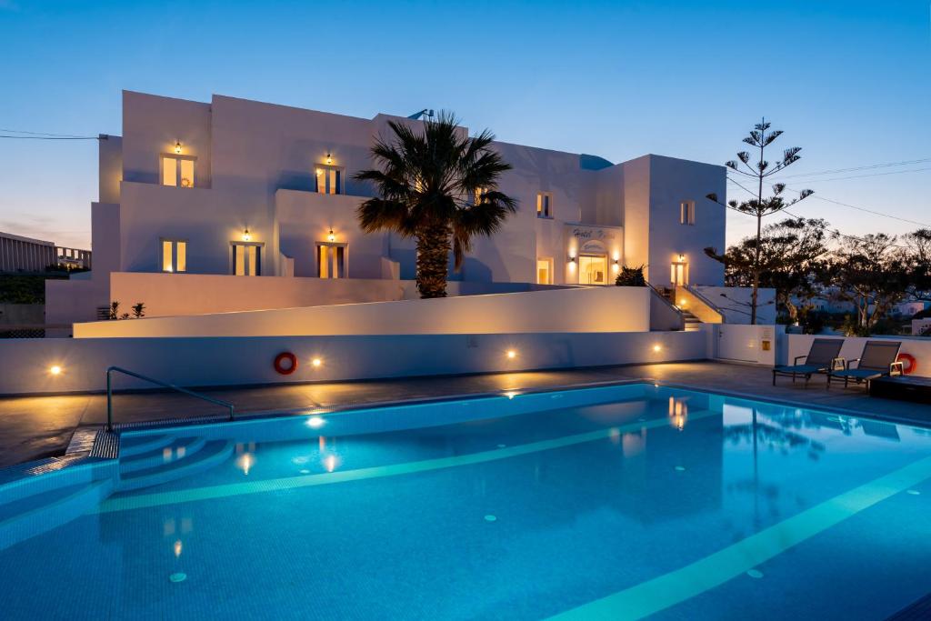 a swimming pool in front of a villa at night at Nikos Hotel in Karterados