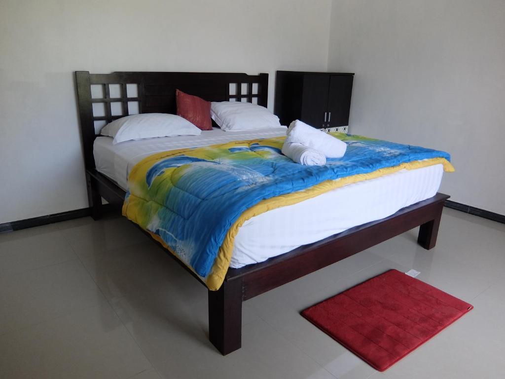 a bedroom with two beds and a red rug at Pondok Wisata Widi in Nusa Lembongan