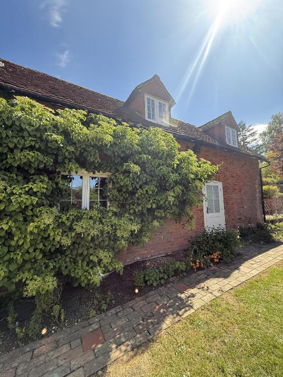 a brick house with ivy on the side of it at The Coach House in Halstead