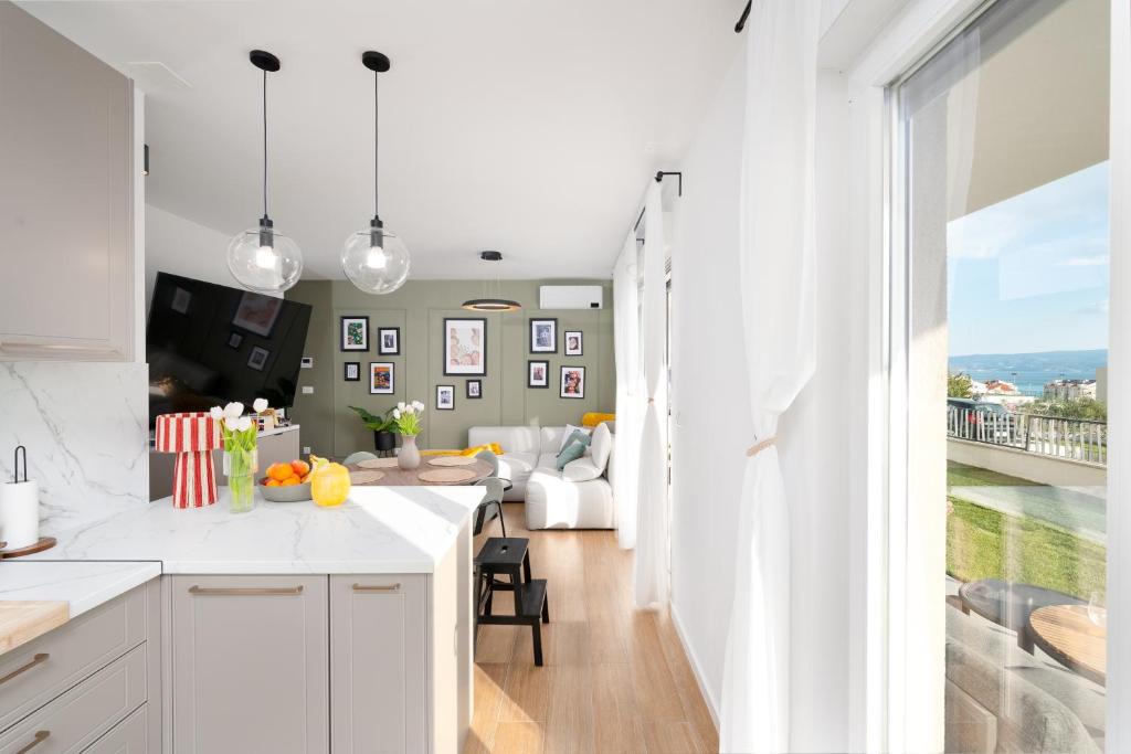 a kitchen with white cabinets and a living room at Lejla Garden Apartment in Podstrana