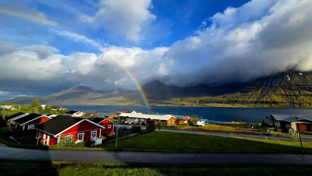 a rainbow over a town with houses and a mountain at Cozy Fjord Loft in Reyðarfjörður