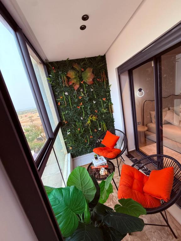 an apartment balcony with orange pillows and a garden at Votre escapade d été à deux pas de la plage in Kenitra