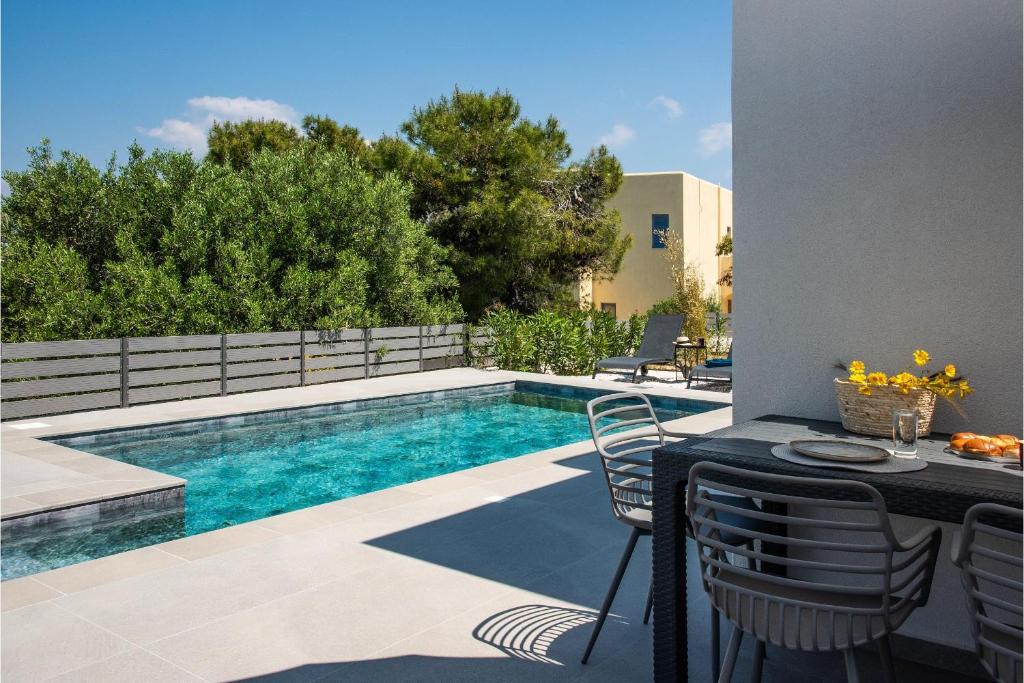 a swimming pool with a table and chairs next to it at Exis Seaview in Vathí