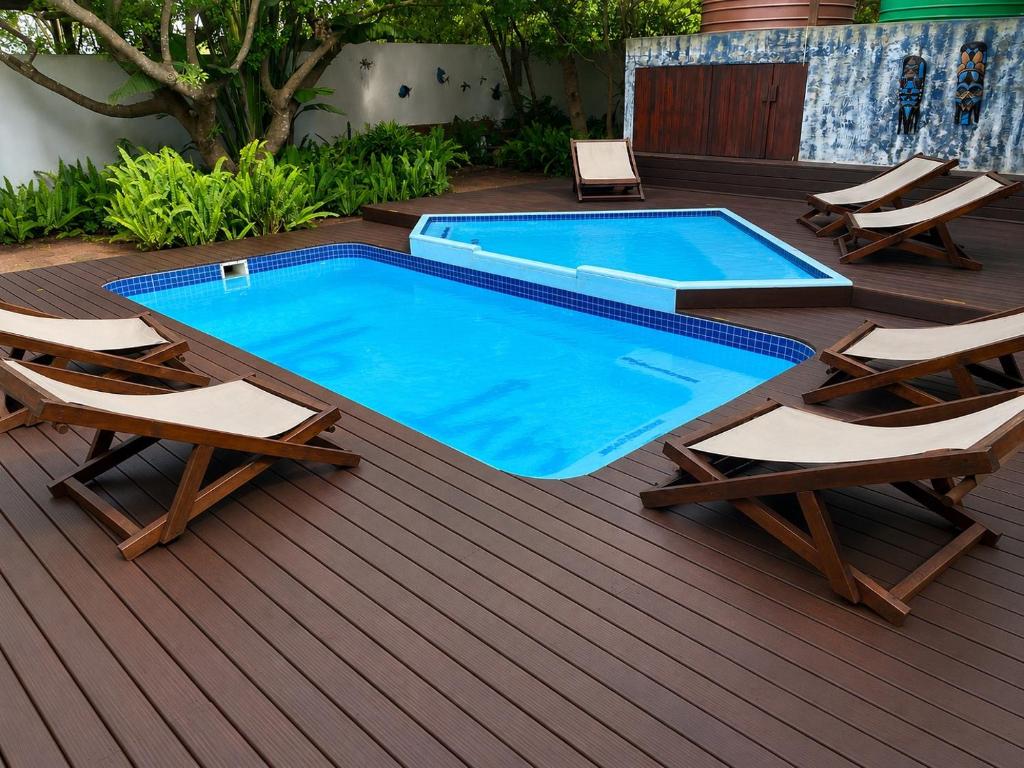 a swimming pool on a deck with two lounge chairs at Moz Inn - Coconut View Resort in Lopes
