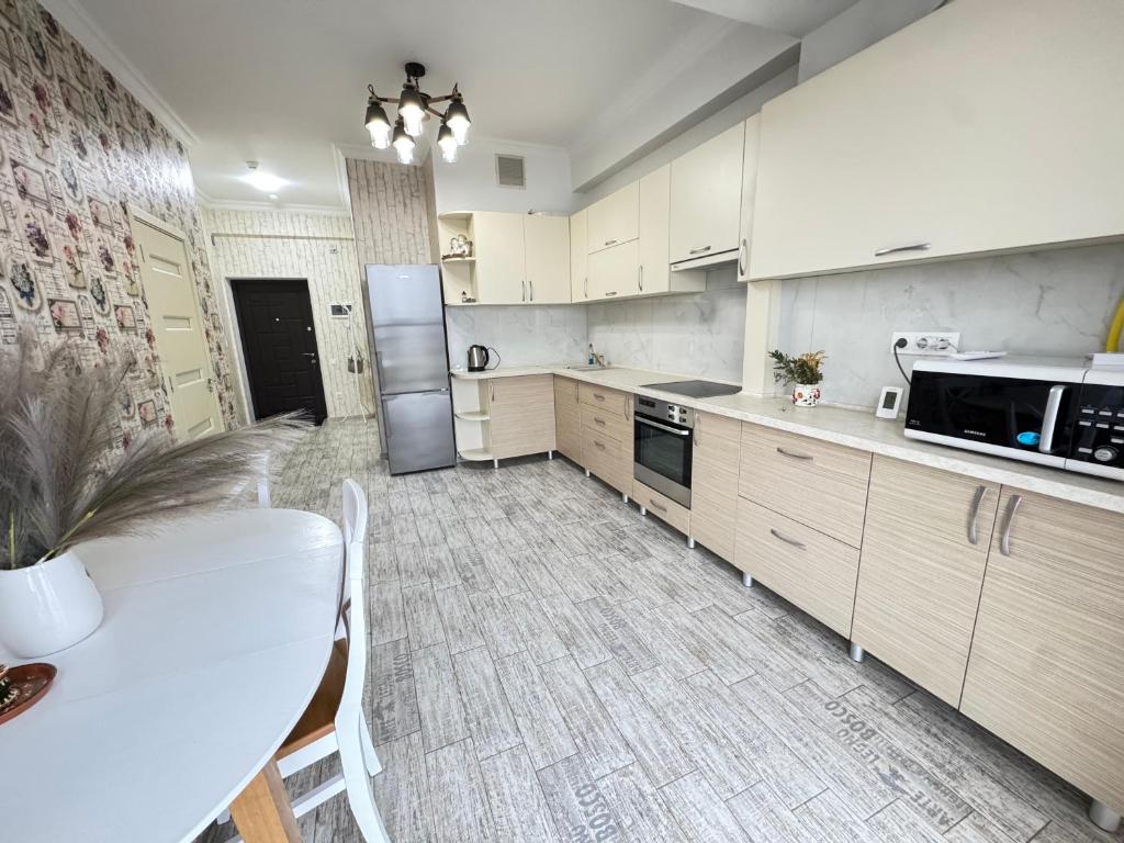 a kitchen with white cabinets and a table and a refrigerator at RentDay Botanica in Chişinău