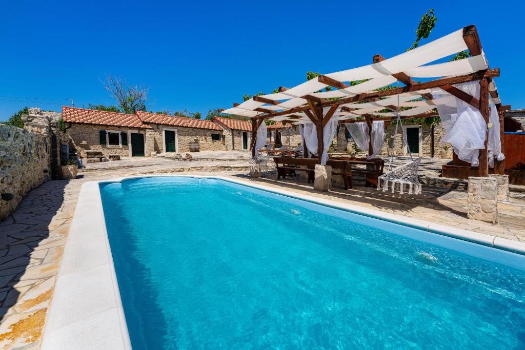 a swimming pool with a pergola and a house at My Dalmatia - Hilltop Paradise with private pool, sauna and Jacuzzi in Kula Atlagić