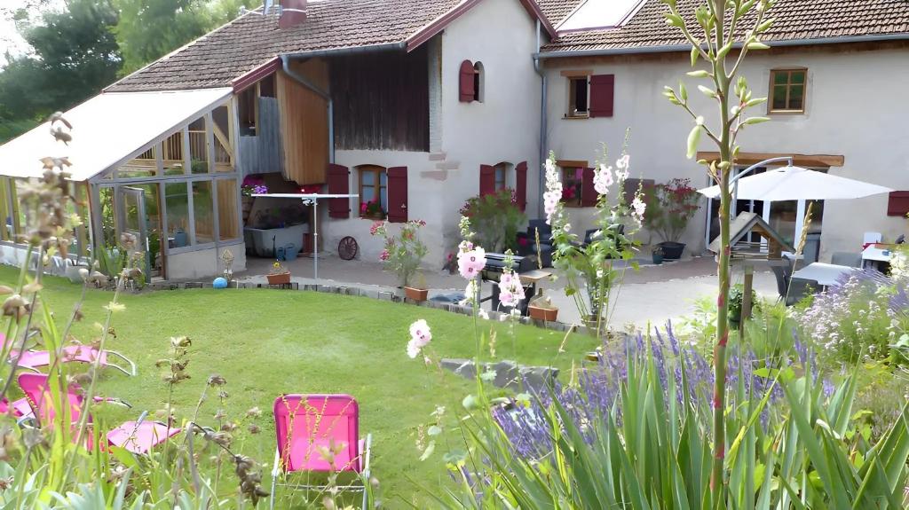 a house with a yard with a pink chair in front of it at Maison d'hôtes - Relais De La Poste in Gerbépal