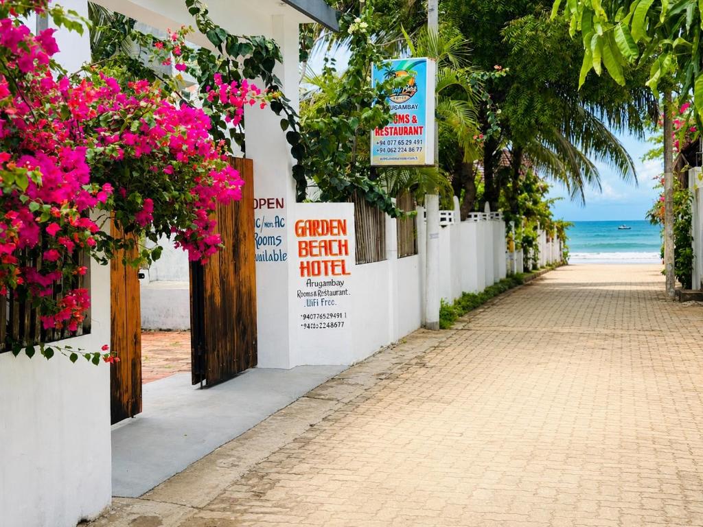 a street with pink flowers on a white building at Garden Beach Hotel in Arugam Bay