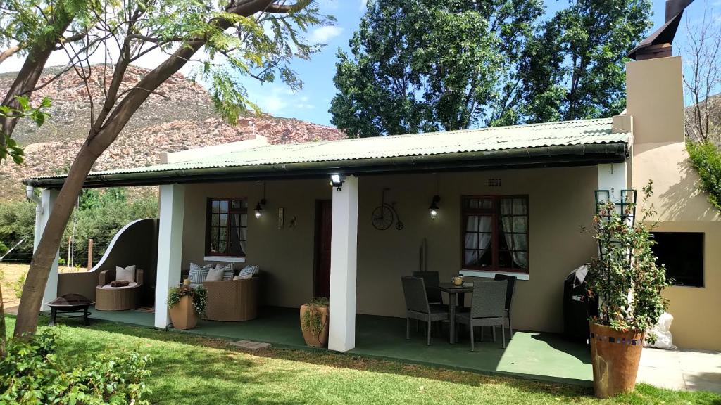 a house with a patio with a table and chairs at Cottage on Long in Montagu