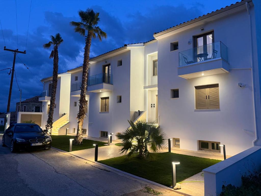 a white building with palm trees in front of it at Latsis Suites in Moláoi