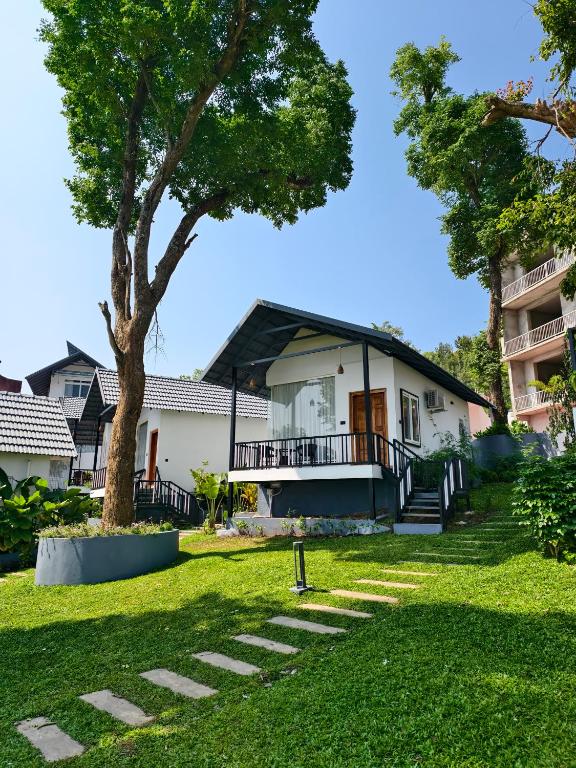 a house with a tree in the yard at Coorg Tiger Eye Backwater Resort in Kushālnagar