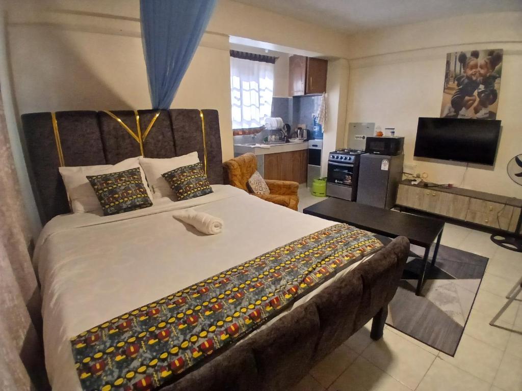 a bedroom with a large bed and a kitchen at Maridadi place in Kakamega
